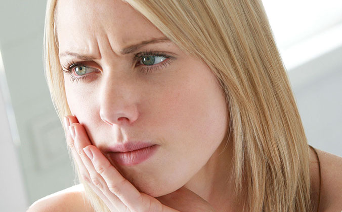 Девушка держит щеку